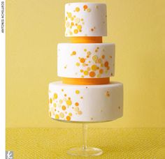 a three tiered cake sitting on top of a glass stand with yellow polka dots