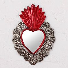 a heart shaped mirror hanging on the side of a white wall with a red tint