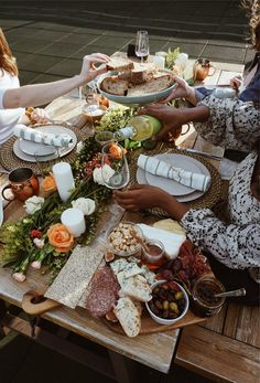 three women sitting at a table with food on it