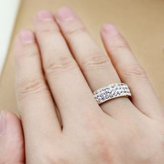 a woman's hand with a diamond ring on her left hand and the other hand holding it