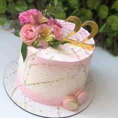 a pink and gold cake with flowers on top