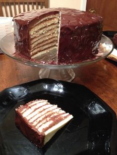 a chocolate cake with white frosting and one slice cut out on a black plate