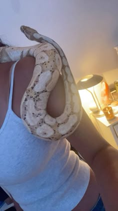 a woman holding a large snake in her hand while standing next to a counter top