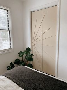 a bedroom with a bed and a plant in front of the door that is open