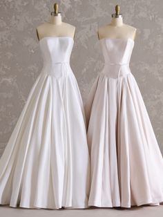 two white dresses on mannequins in front of a wall