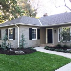 a gray house with black shutters and green grass in the front yard is shown