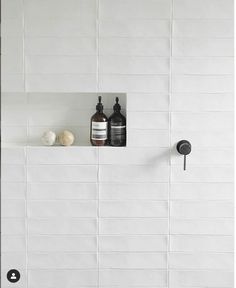 two bottles are sitting on a shelf in the bathroom, one is black and white