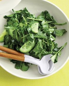 two white bowls filled with green vegetables and chopsticks