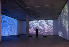 a person standing in an empty room with projected images on the walls and flooring