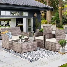 an outdoor living area with wicker furniture and potted plants in front of the house