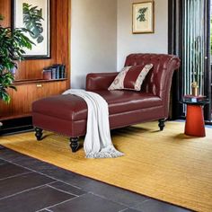 a living room with a red leather chair and ottoman in front of a sliding glass door