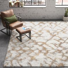 a chair and ottoman in a room with brick walls, windows, and an area rug on the floor