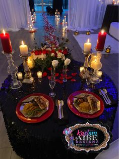 the table is set with candles, plates and food for two people to eat at