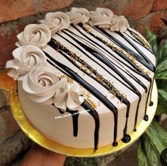 a cake with white and black icing on it sitting on a gold platter