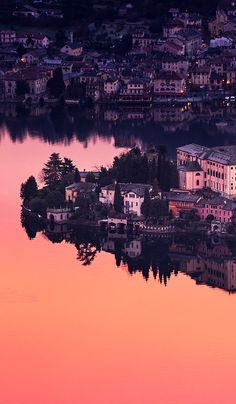 an island in the middle of a body of water with buildings on it at sunset