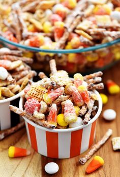 two bowls filled with candy corn and marshmallows on top of a wooden table