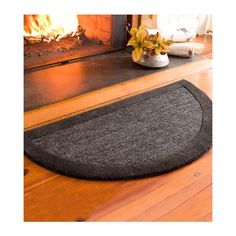 a door mat on the floor in front of a fire place with a potted plant next to it