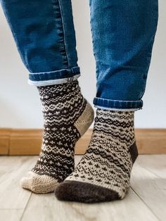 a person standing on the floor with their feet up wearing socks that are knitted in different colors