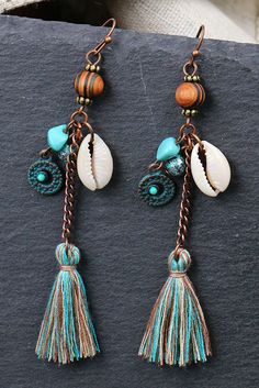 two pairs of earrings with shells and tassels hanging from the end of each ear