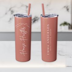 two pink tumblers sitting on top of a white countertop next to each other