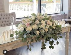 a bouquet of flowers sitting on top of a wooden table next to a glass window