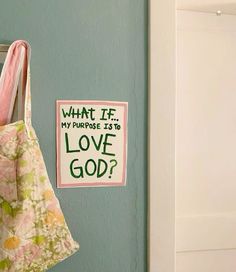 a bag hanging on the wall next to a sign that says what if my purpose is to love god?