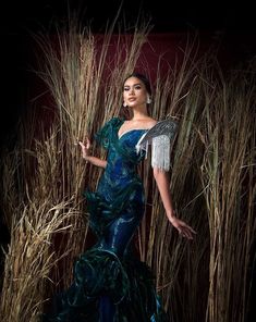 a woman in a blue dress standing next to tall grass