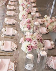 a long table is set with pink and white flowers, candles and napkins on it