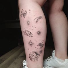 a woman's leg with tattoos on it and various objects in the sky above her