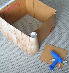 an open cardboard box sitting on top of a floor next to a pair of scissors