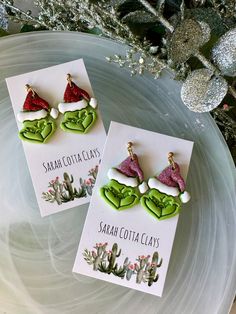 two christmas themed earrings sitting on top of a plate