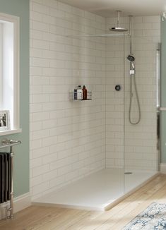 a bathroom with a shower, toilet and rug on the wooden floor in front of it