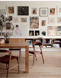 a wooden table sitting in front of a wall with pictures on it