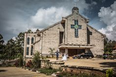 a bride and groom standing in front of a church