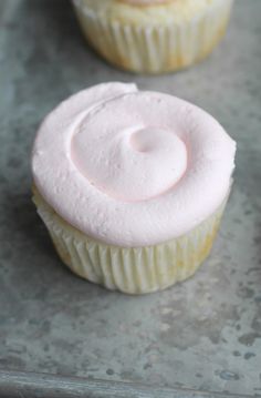 three frosted cupcakes sitting on top of a baking sheet