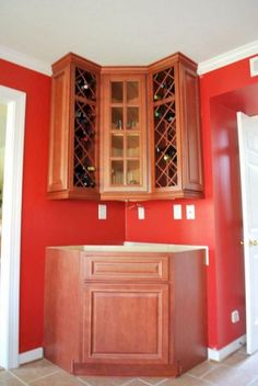 an empty kitchen with red walls and wooden cabinetry in the center, along with tile flooring