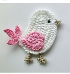 a crocheted white bird with pink breast on it's tail and wings