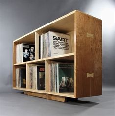 a wooden book shelf filled with books on top of each other and magazines in front of it