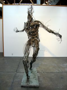 a sculpture is shown in front of a white wall and some wires on the ground