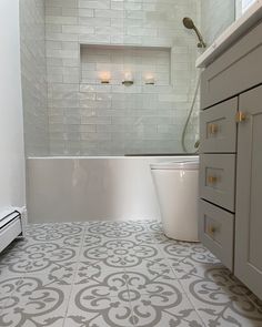 a bathroom with white and gray tile flooring next to a tub in the corner