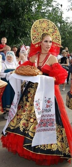 a woman in red and gold dress carrying a pie