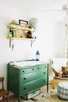 a baby's room with a green dresser and teddy bear on the shelf next to it