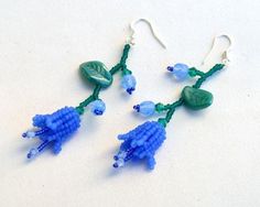 blue beads and green leaves are hanging from earrings