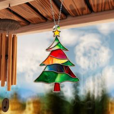 a stained glass christmas tree ornament hanging from a wooden roof with wind chime