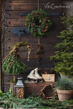 christmas wreaths hanging on the side of a wooden wall next to potted plants