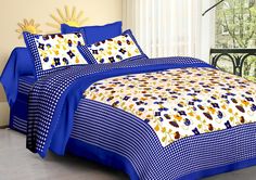 a bed with blue and yellow comforters on top of it next to a window