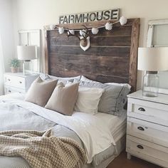 a bed with pillows and blankets in a bedroom next to a lamp on a dresser