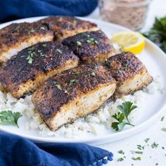 three pieces of fish on top of white rice and garnished with parsley