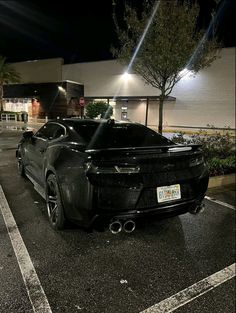 a black sports car parked in front of a building at night with its lights on