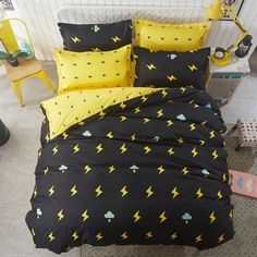 a bed covered in black and yellow sheets with lightning prints on them, sitting next to a chair